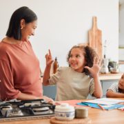 A mother helping children with homework in the kitchen